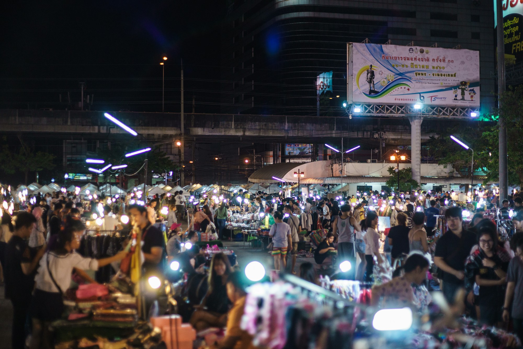 Crowds browsing food and market stalls at a Bangkok night market