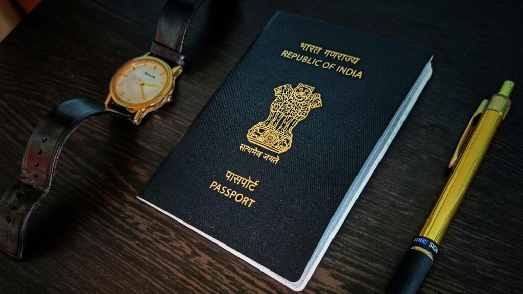 Indian passport on a wooden table next to a wristwatch and a pen, ready for a first international trip