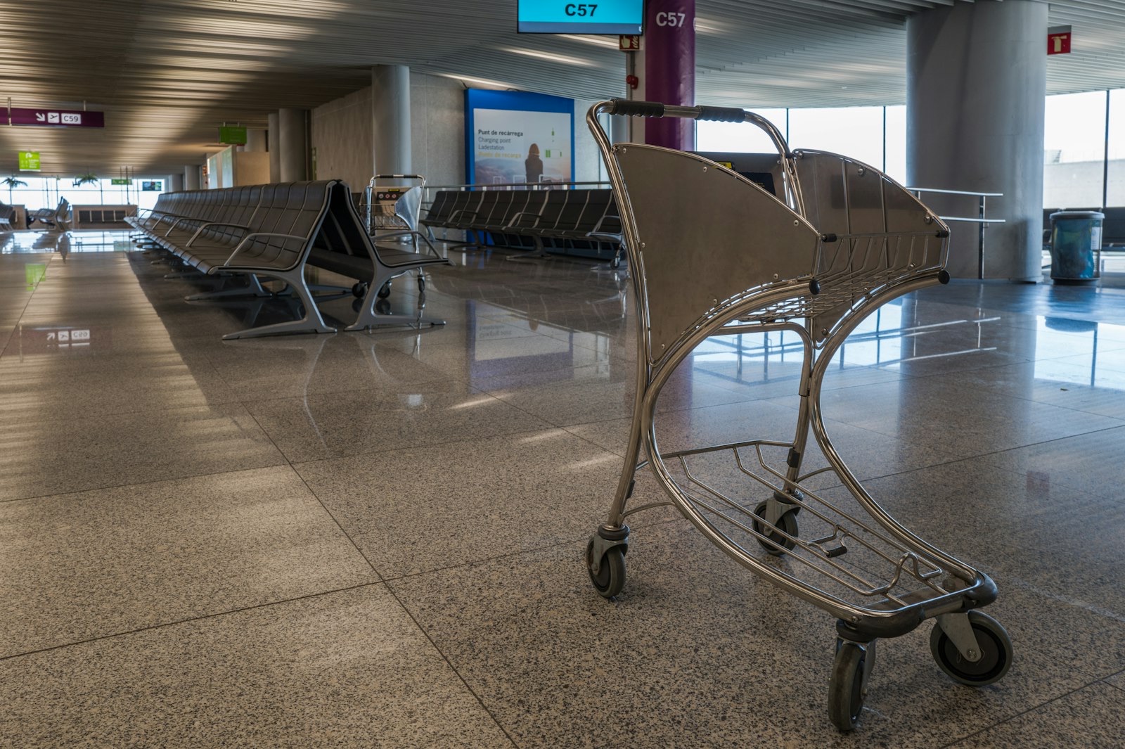 Empty airport gate seating area with a luggage trolley, the kind of scene travelers face when a flight is canceled or delayed