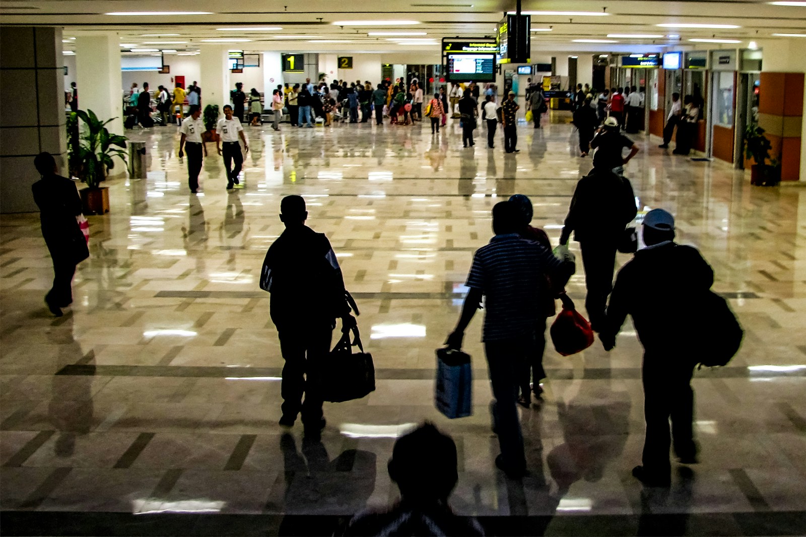 Travelers with bags walking through a busy airport terminal between flights